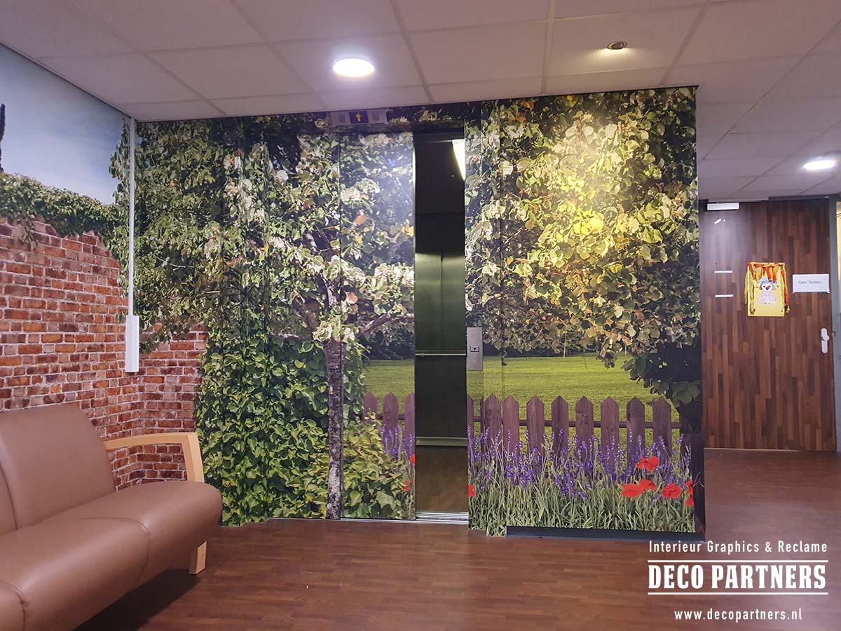 Fotorealistische liftbestickering voor een psychogeriatrische afdeling, uitgevoerd als een groen tuinlandschap met bomen, bloemen, een bakstenen muur en een houten tuinhek.