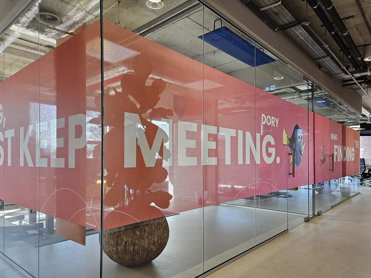 Textielfolie op glazen kantoorwand met opdruk en bedrijfsbranding in moderne kantoorruimte, gemonteerd door DecoPartners