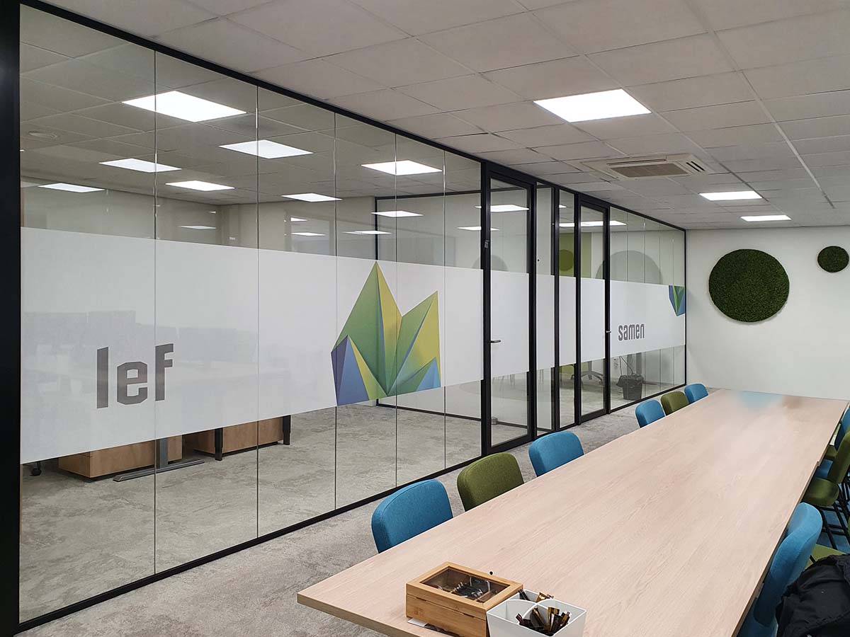 Textielfolie met subtiele linnenstructuur toegepast op glazen kantoorwand. Deze moderne privacyfolie combineert lichtdoorlaat, bedrukking in huisstijl en een warme, natuurlijke uitstraling. Perfect voor moderne kantoren.