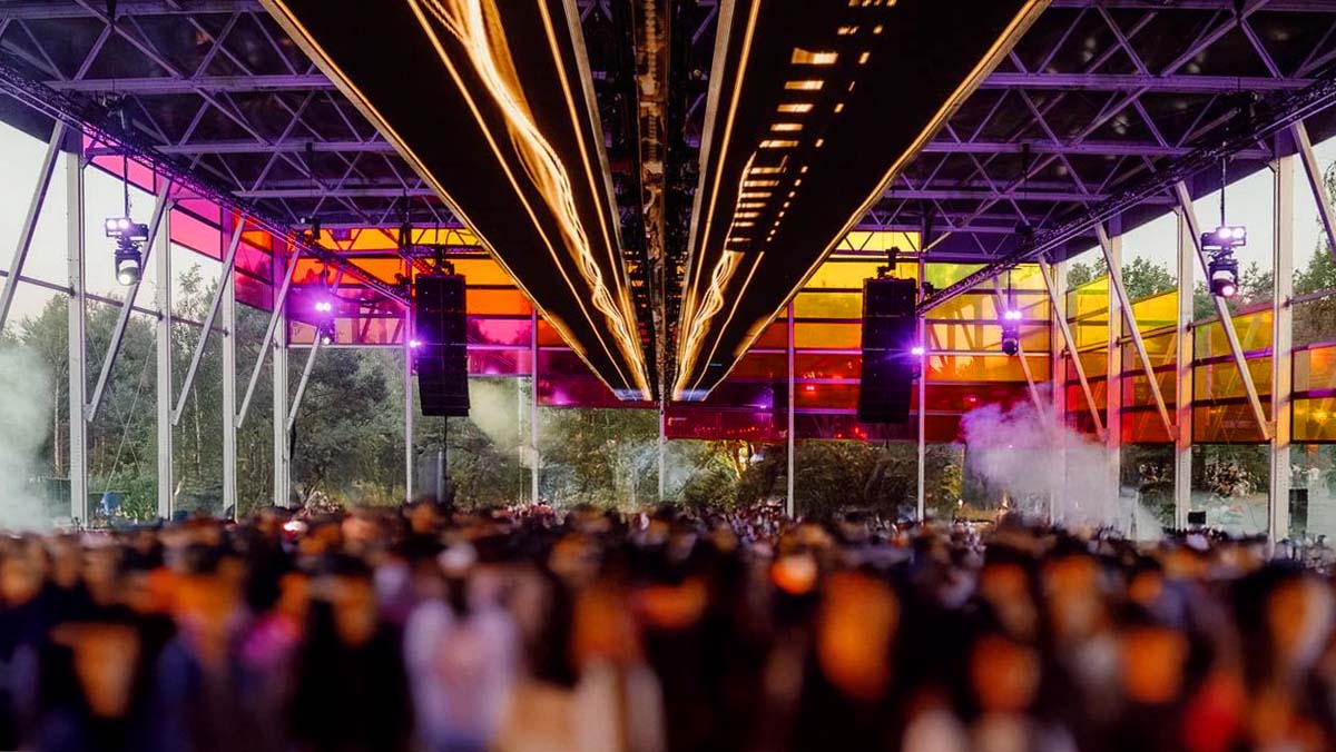 Drukke festivaltent met gekleurde transparante ramen, verlichting en een groot publiek