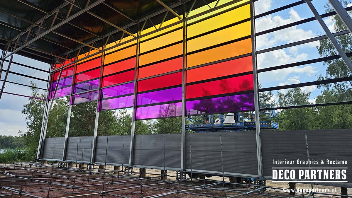 Binnenzijde van de festivaltent tijdens de montage van gele, oranje, rode en paarse transparante glasfolie