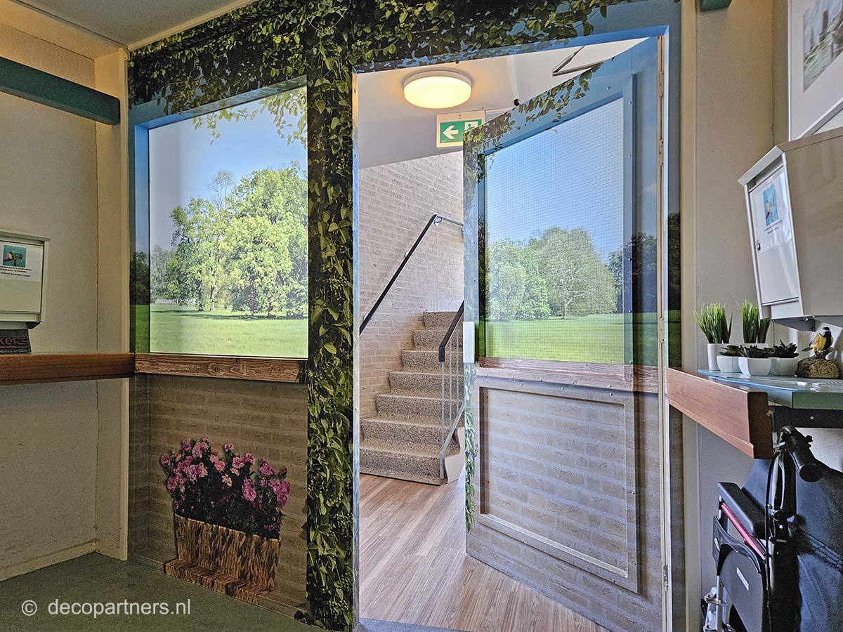 Bestickerde trappenhuisdeur met natuurprint in verpleeghuis – camouflerende oplossing voor rust op dementieafdeling, ontworpen door DecoPartners.