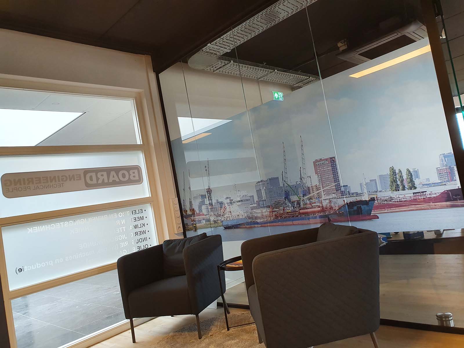 Glaspanelen bij entree van kantoor voorzien van belettering en sfeerfoto