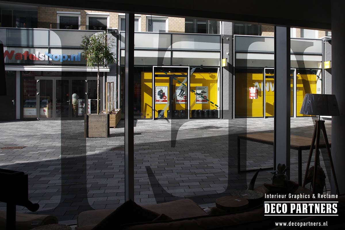 Zicht vanuit de winkel door contourgesneden One Way Vision raambelettering met behoud van uitzicht naar buiten.