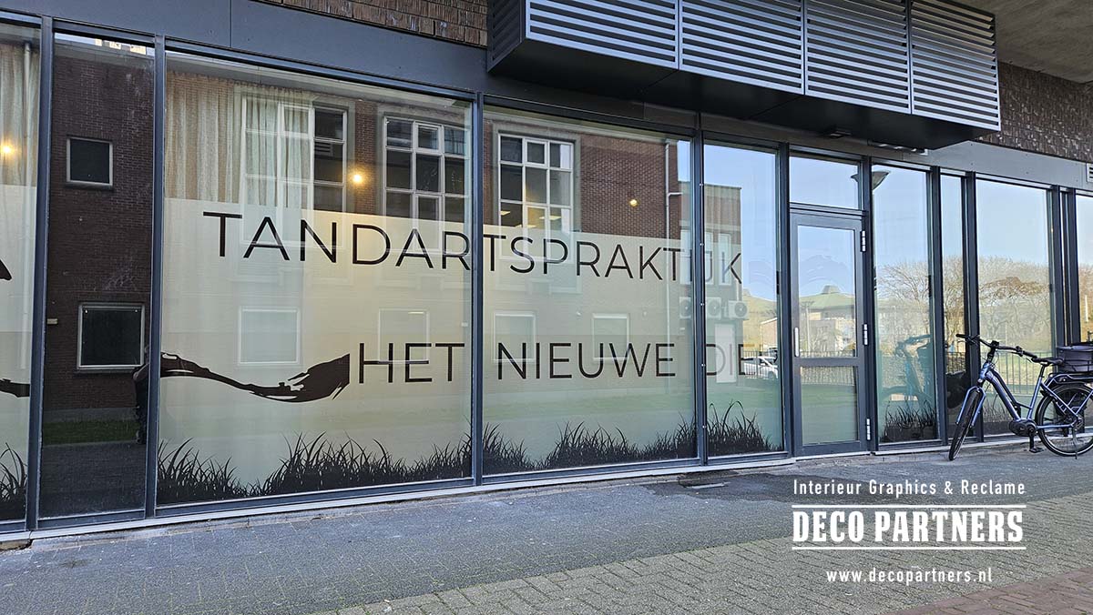 Maatwerk raamfolie op maat gesneden voor een tandartspraktijk - privacyfolie met uniek kustdesign van golven, riet en vogels over de volledige raampartij