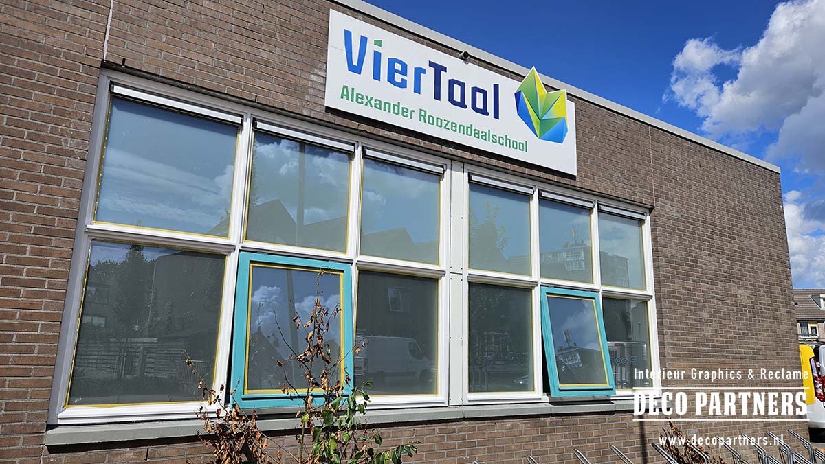 Oud wit gevelbord van VierTaal aan de schoolgevel voordat het werd vervangen door losse gevelletters
