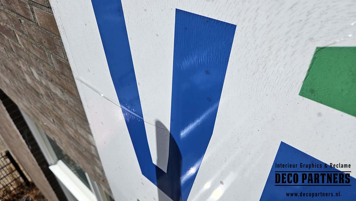 Detail van oud gevelbord waarvan de aangebrachte folie begint los te laten