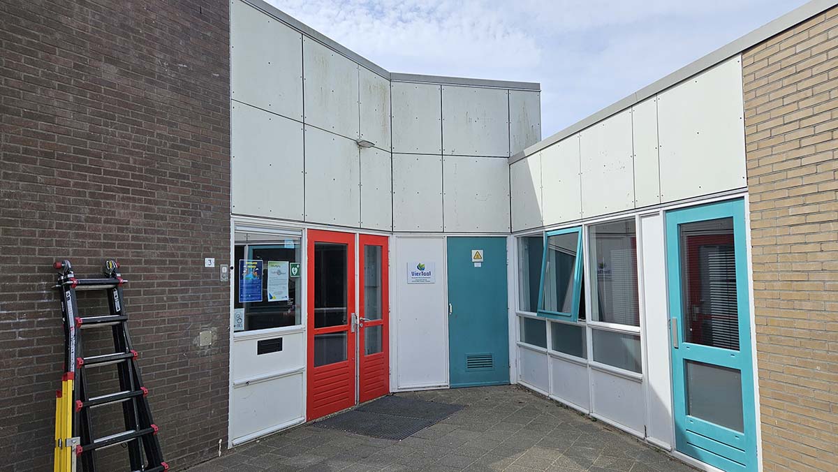 Witte en verkleurde gevelplaten van de schoolentree voordat deze werden voorzien van wrapfolie
