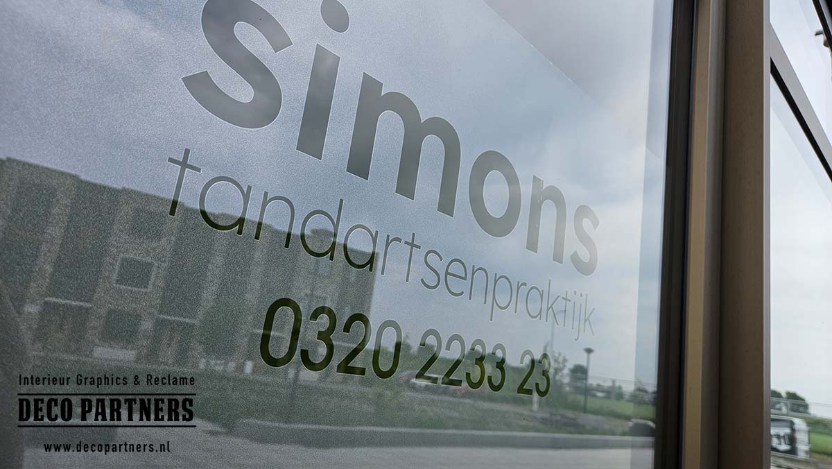 Zandstraalfolie met uitgesneden logo en praktijknaam op raam van tandartspraktijk