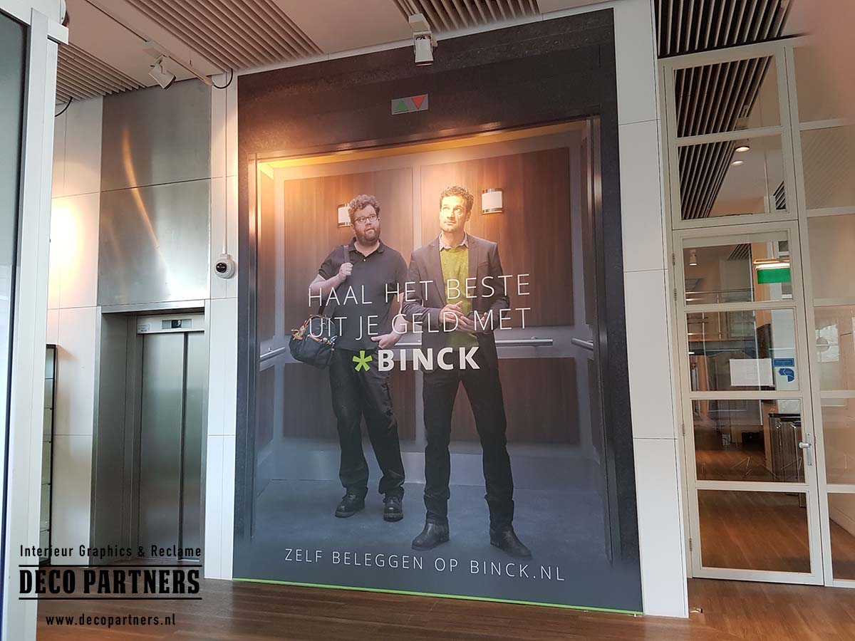Textielwand met bedrukte promotieprint gemonteerd op bestaande hardstenen wand naast lift
