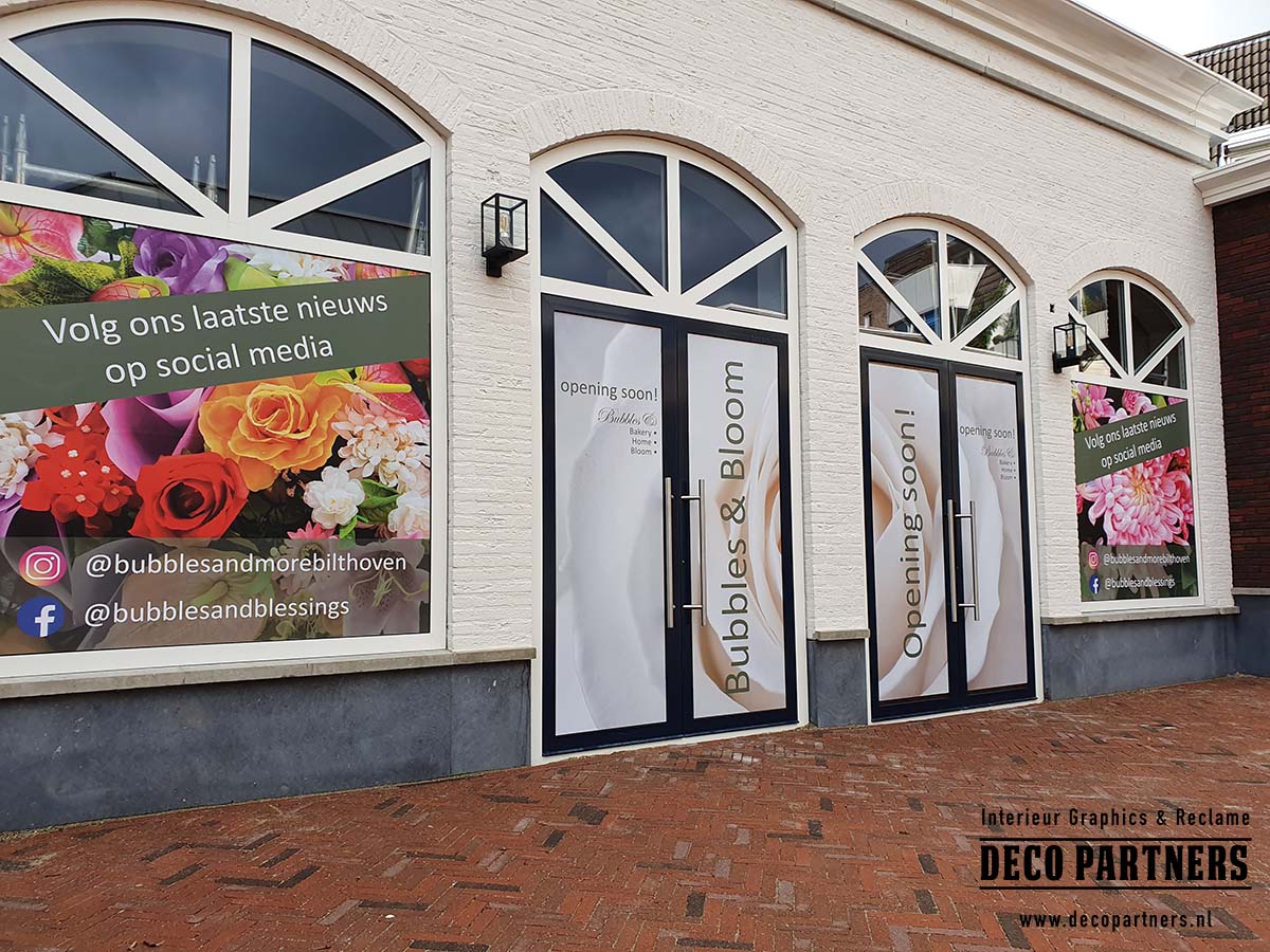 Kleurrijke tijdelijke bestickering op ramen en deuren van een winkelpand als aankondiging van een nieuwe opening.