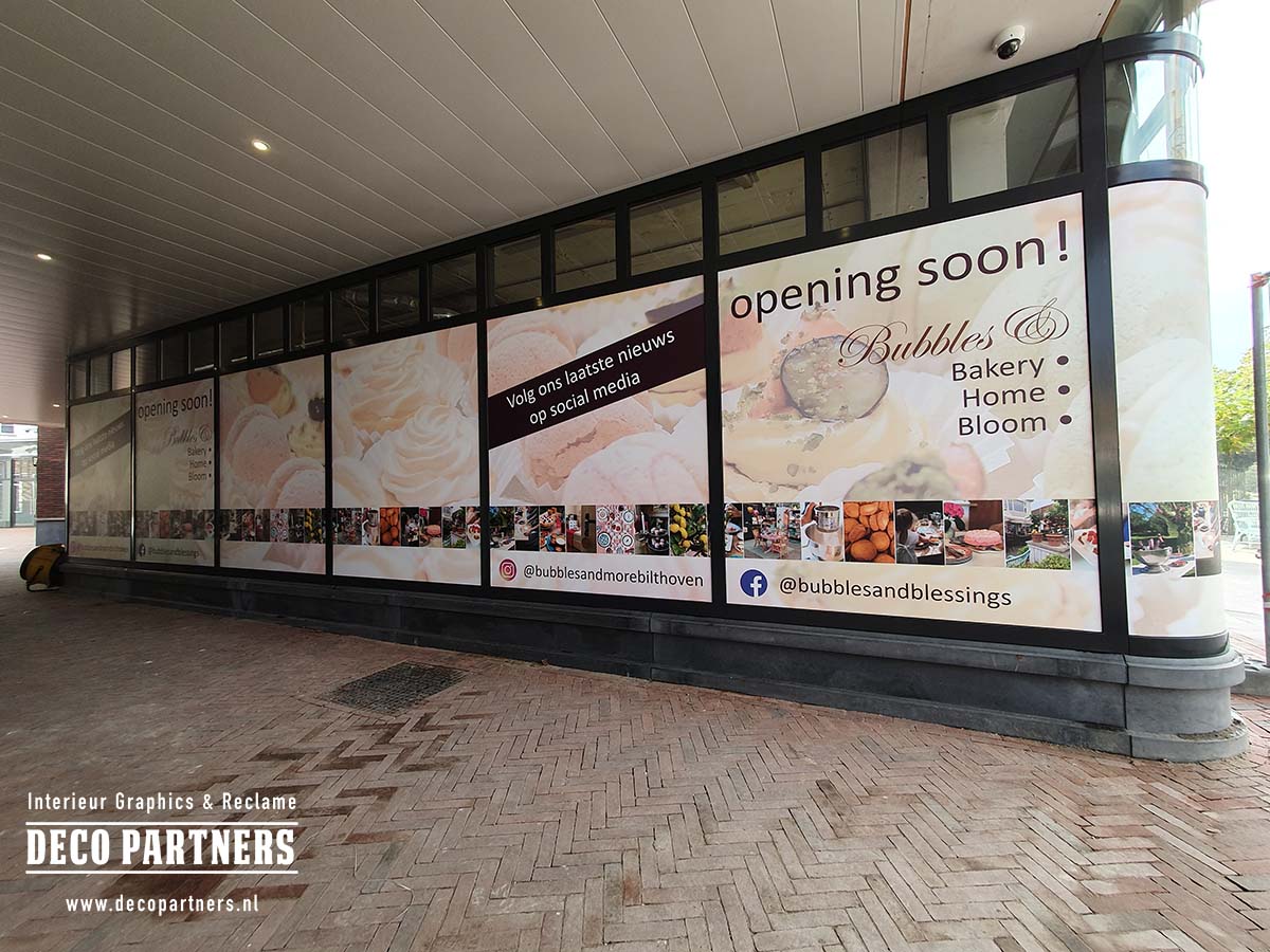 Tijdelijke raambestickering met Opening Soon reclame over meerdere grote winkelruiten.