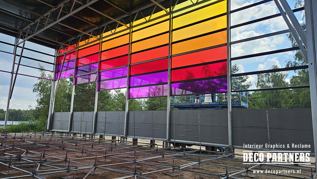 Grote glazen gevel van evenementenlocatie tijdelijk voorzien van gekleurde folie over meerdere raampartijen.