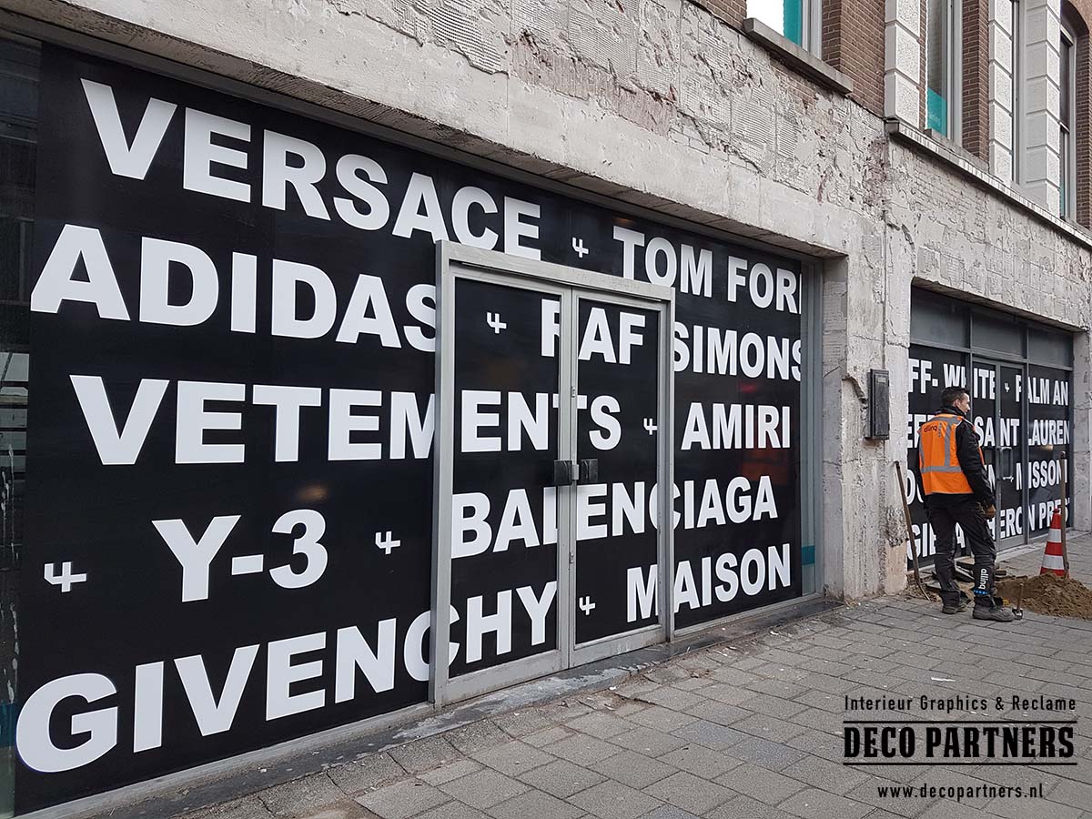 Tijdelijke One Way Vision raamfolie met grote reclame-uiting op de ramen van een winkelpand.