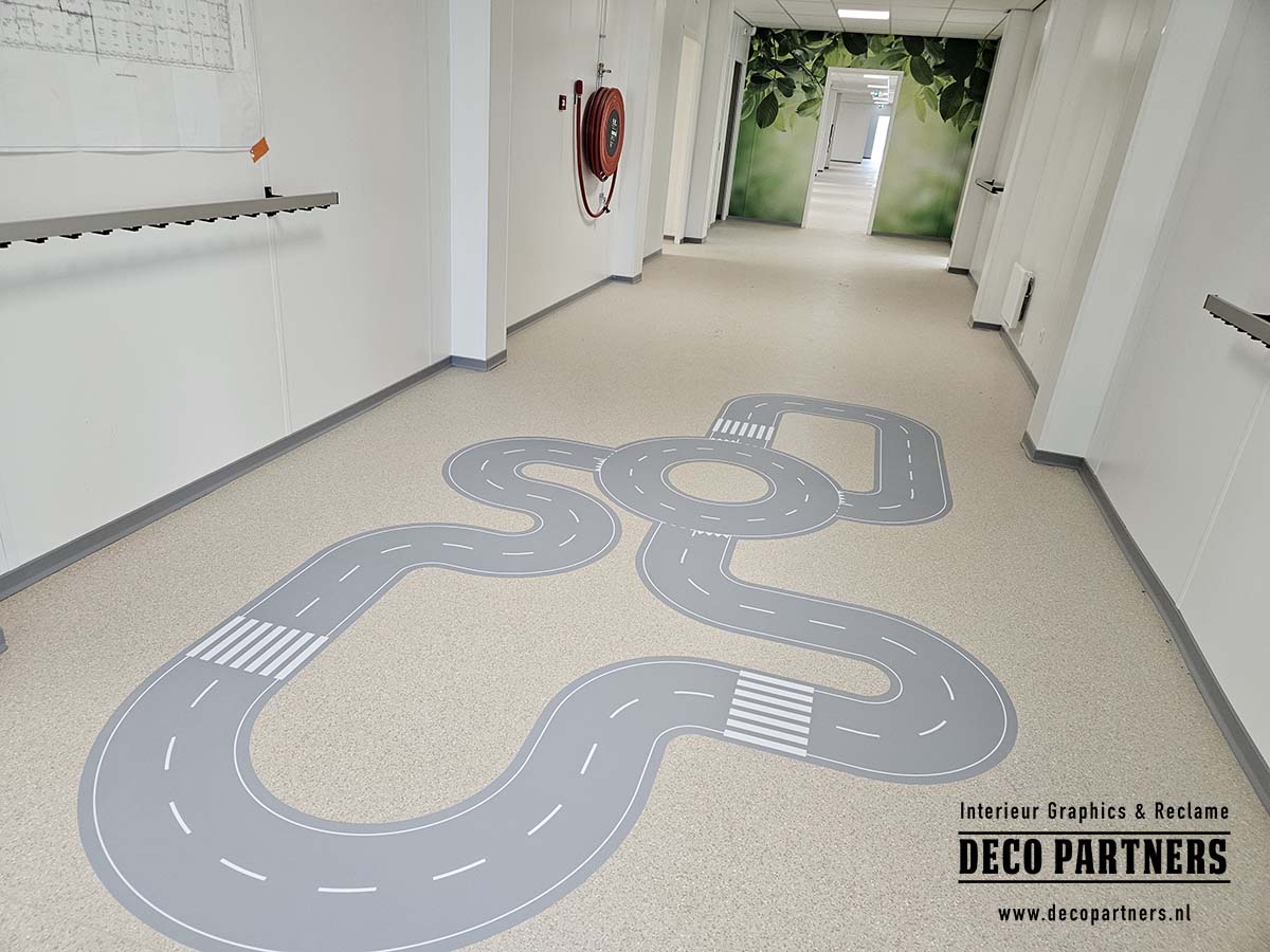 Grote grijze autobaan van antislip vloerfolie in de gang van een tijdelijke kinderopvanglocatie.