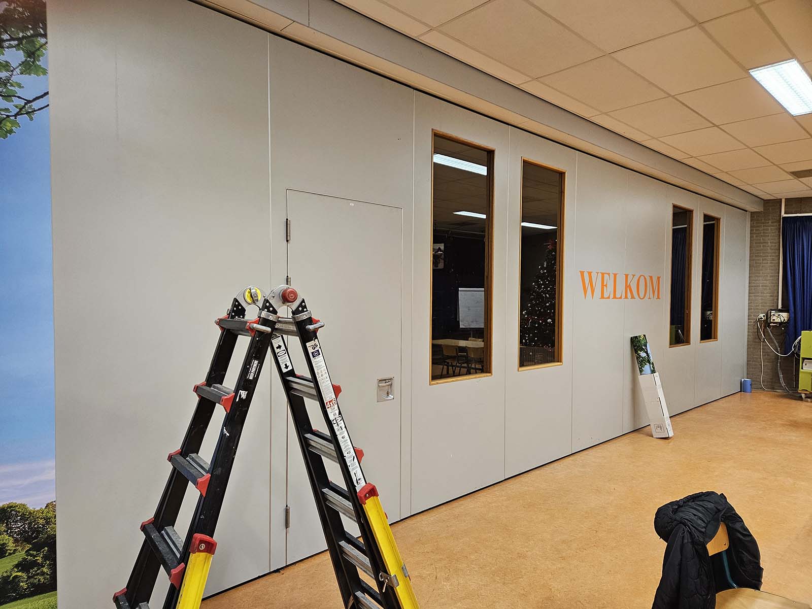 Voorafgaand aan de transformatie: grijze aula wand klaar voor folieprint makeover in Utrecht.