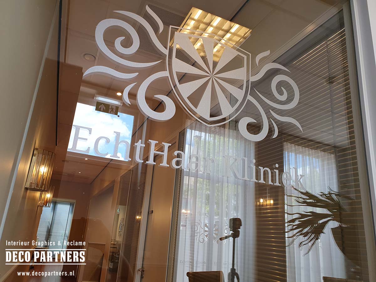 Logo en tekst uit zandstraalfolie gesneden en aangebracht op een transparante glazen wand.