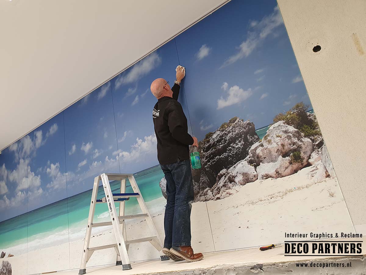 Monteur plaatst aluminium fotopanelen met tropische strandprint in zwembad